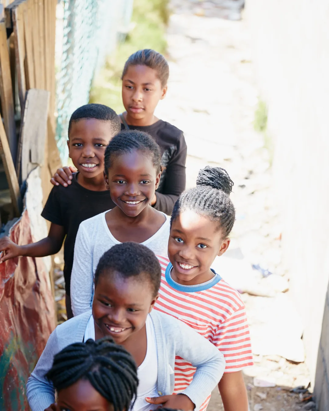 A group of smiling children standing together outdoors in their neighbourhood